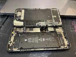 iPhone water damage repair in progress at TekRenewed repair bench Corroded iPhone motherboard being cleaned after liquid exposure Disassembled iPhone showing water-damaged components iPhone undergoing ultrasonic cleaning process after water spill