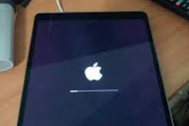 iPad displaying Apple logo stuck on boot - software issue diagnostic Technician repairing iPad software using MacBook and tools iPad screen showing restore mode - iOS troubleshooting in progress Refurbished iPad undergoing software repair at TekRenewed