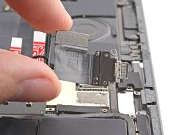 iPad charging port being replaced by TekRenewed technician Close-up of iPad lightning port repair with soldering tools Disassembled iPad showing charging port and flex cable iPad showing charging issue being diagnosed for port damage